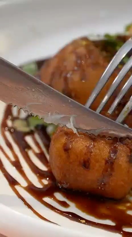 Dados de bacalao en tempura de miel sobre un trazo de salsa oscura