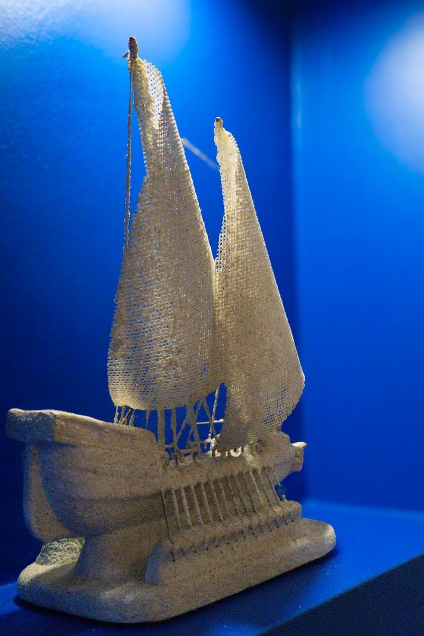 Barco de vela blanco, de artesanía, en una hornacina iluminada de azul