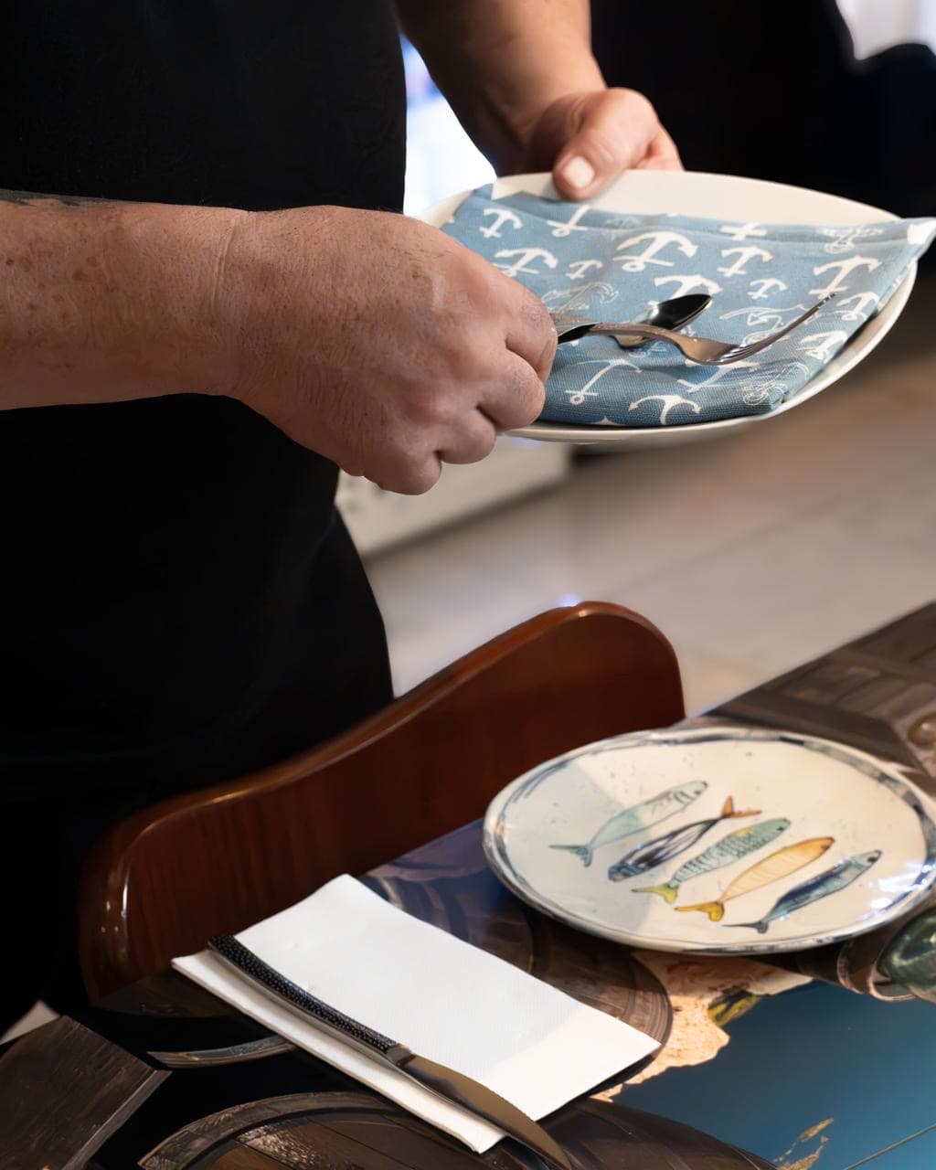 Montaje de mesa con servilleta de anclas y plato pintado con sardinas